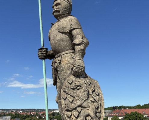 Vom höchsten Punkt des Gebäudes überwacht die Figur nicht nur das Markttreiben, sondern auch das Baugeschehen. Sie selbst bleibt während ihrer Sanierung ebenfalls vor Ort.